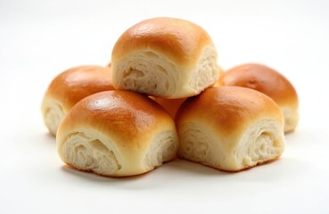 Pile of golden dinner rolls rests on a white surface. These fresh baked buns are soft and inviting perfect for breakfast or a light meal. They appear delicious and ideal for food photography.