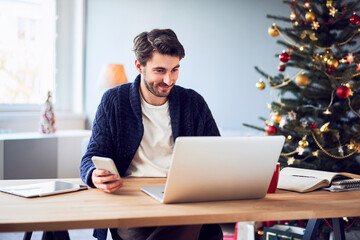 Young man doing Christmas shopping online paying with mobile phone