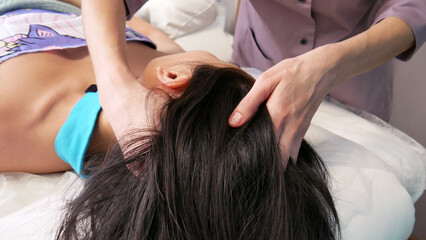 Fototapeta premium Close-up of a masseuse's hands giving a head massage to a long-haired girl