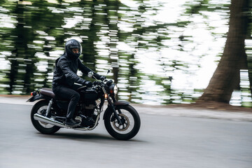 Fototapeta premium Driving fast. Man in leather clothes on motorcycle is on the road