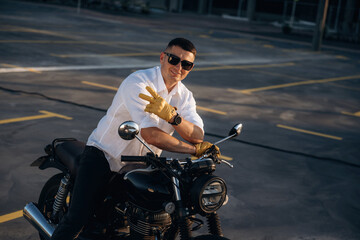Happy, smiling and showing hand gesture. Man is outdoors with his motorcycle