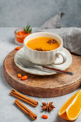 Sea buckthorn herbal tea in a cup on a wooden board on a light background