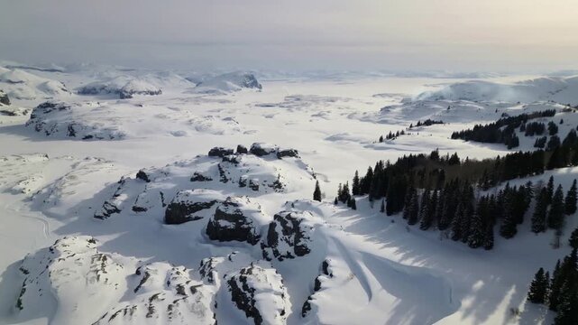 An ultra-slow aerial descent over vast frozen plains and dark pine forests under pale winter light, revealing an ancient, untouched landscape with distant smoke and an epic, desolate calm.
