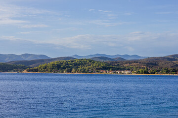 Fototapeta premium View of a coastal village with lush green hills and blue sea