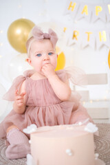 little beautiful blue-eyed girl celebrates her first birthday and tastes her first birthday cake