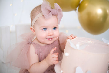 little beautiful blue-eyed girl celebrates her first birthday and tastes her first birthday cake