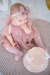 little beautiful blue-eyed girl celebrates her first birthday and tastes her first birthday cake