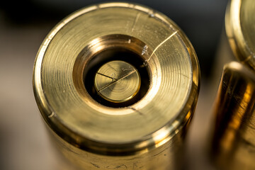 Close up view of the primer pocket and firing pin mark on the base of a spent brass cartridge casing