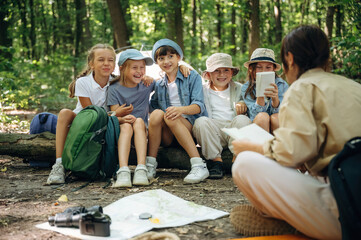 Laughing at story, smiling. Woman is doing tour for group of kids in the forest