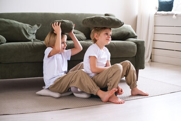 kids boys have fun with pillows, sitting on the living room floor