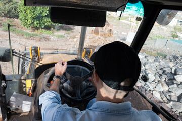 Young man driving a backhoe loader in the countryside