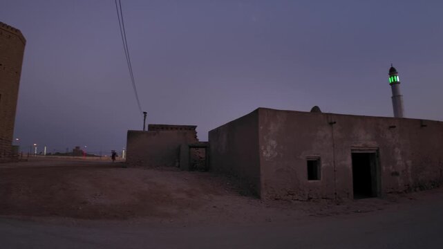 Ancient Mirbat stone fort with defensive towers and a flag flying high, standing in Mirbat city at dusk, highlighting historic Omani architecture and cultural heritage in Dhofar, in Oman at sunset