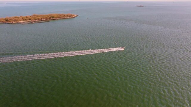 Aerial drone view of Hoffman Island in New York Harbor, a small historic island surrounded by calm open water with the distant coastline visible on the horizon.