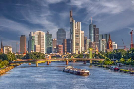 Frankfurt Skyline over Main River with Cargo Barge and Eiserner Steg Bridge during Golden Hour Sunset