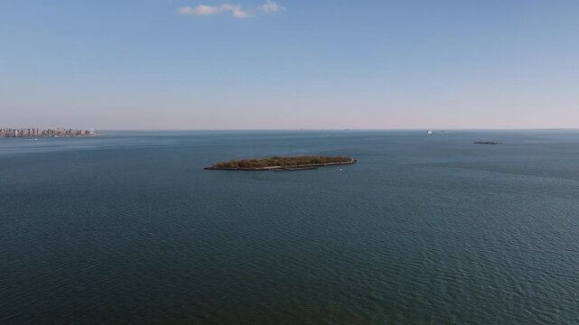 Aerial drone view of Hoffman Island in New York Harbor, a small historic island surrounded by calm open water with the distant coastline visible on the horizon.