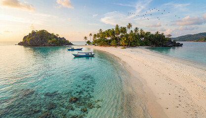 Tropical beach with palm trees and boats at sunset