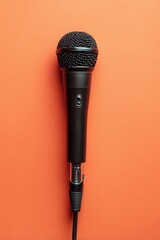 Photo of a black microphone with a long cable, top view, red background.