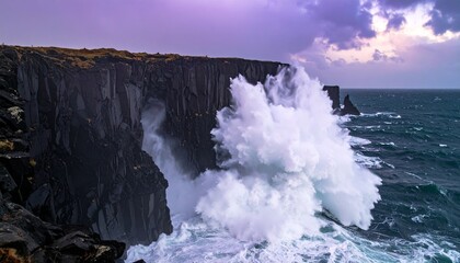 Huge waves collide with dark jagged cliffs along the coast creating a dramatic spray of white water under a moody sky