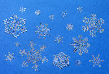  Merry Christmas and Happy New Year. Winter ornament of silver snowflakes on blue background. Christmas  festive backdrop.  Top view, flat lay, close-up, mock up