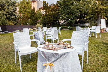 Tables and chairs with teacups on a green lawn for a celebration
