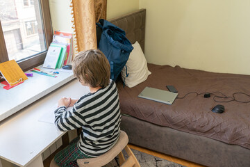 Boy doing homework at a desk in his bedroom. Student learning at home. Homeschooling concept