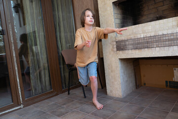 Young boy balancing on one leg at home. Child doing a yoga pose on the patio