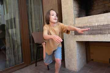 Young boy exercising and balancing on one leg at home. Child playing on the patio
