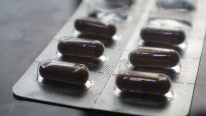 Brown Medical Capsules in Blister Pack on Dark Background.
