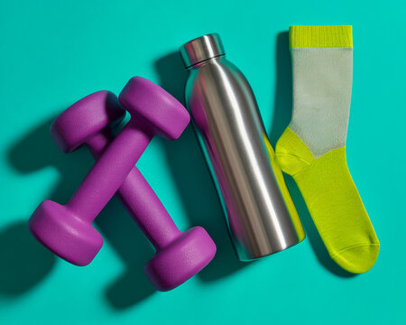 Bright workout items on a teal background, including dumbbells, a water bottle, and a sock, ready for fitness activities