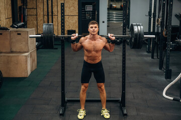Exercise of squats with heavy barbell. Athletic man is in a gym