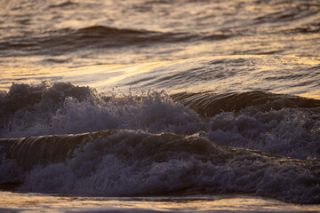 A sunset colors the sky and lights up ocean waves, creating a tranquil atmosphere as night approaches
