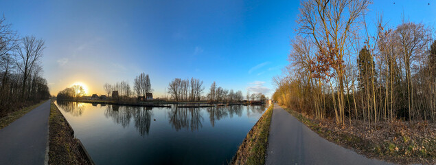 A stunningly beautiful riverbank view at sunset showcases vibrant colors along with calm water reflections
