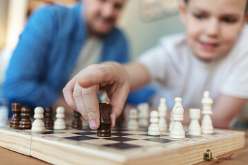 Playing, hands and father with kid for chess in home for learning, development or bonding. Teaching, competition and dad with boy child for board game with checkmate for problem solving skills.