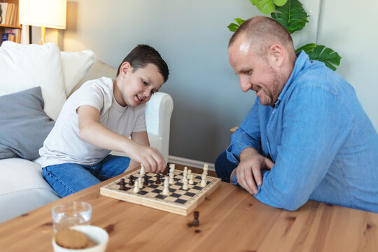 Adorable boy, men and together by board for queen, king and pawn for contest and family bonding. Son and father playing chess together on weekend at home.