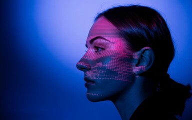 Stunning profile portrait of woman illuminated by vibrant digital data projection in deep blue light