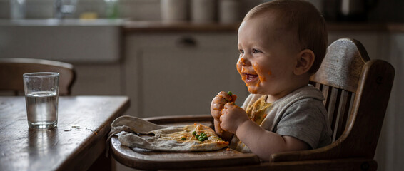 Baby enjoys food while sitting in high chair at home
