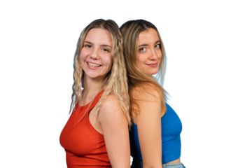 Two young women friends standing back to back smiling
