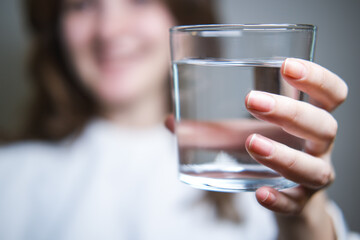 The woman hands her clean glass of water to the camera.