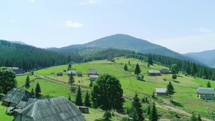 Green field and mountain hill with cottage houses in village