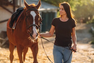 Obraz premium Black shirt and blue jeans. Woman is with horse on the farm