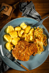 Breaded pork neck cutlet served with potatoes and salad.