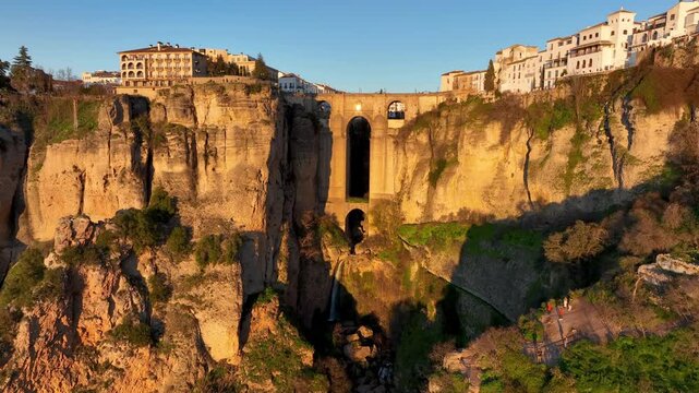 ancient arch over canyon, aerial view of rugged landscape with historic bridge and mountain range. Ronda. Spain