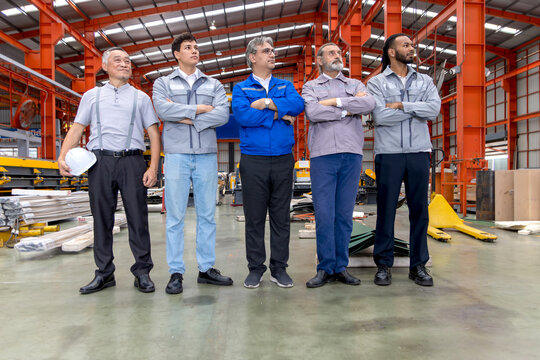 Group of engineers standing line up in manufacturing factory. Corporate engineering workers standing confidently in industrial setting. Diverse professional team look in same direction with visions. - Powered by Adobe