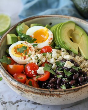 Healthy grain bowl with soft-boiled eggs, avocado, black beans, and tomatoes