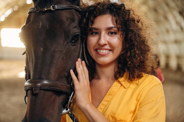 Feeling good, taking care of animal. Beautiful young woman is with horse in hangar