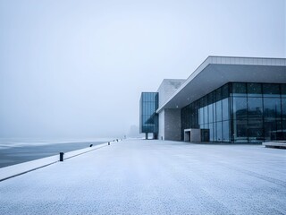 Obraz premium A glass museum stands silent by a frozen lake under falling snow
