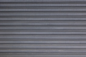 Obraz premium Close-up of a metal shutter showing its grey, gritty surface and worn, textured finish.