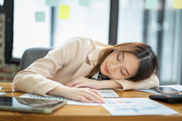 Exhausted professional woman sleeping at desk in modern office environment document overload focus on stress relief