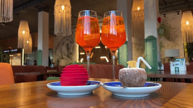 wooden table desserts Coco and Rose jelly cheesecake and two glasses of Aperol