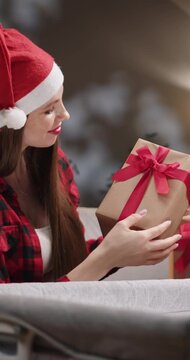A woman wearing a Santa hat and a red plaid shirt smiles while working on a project